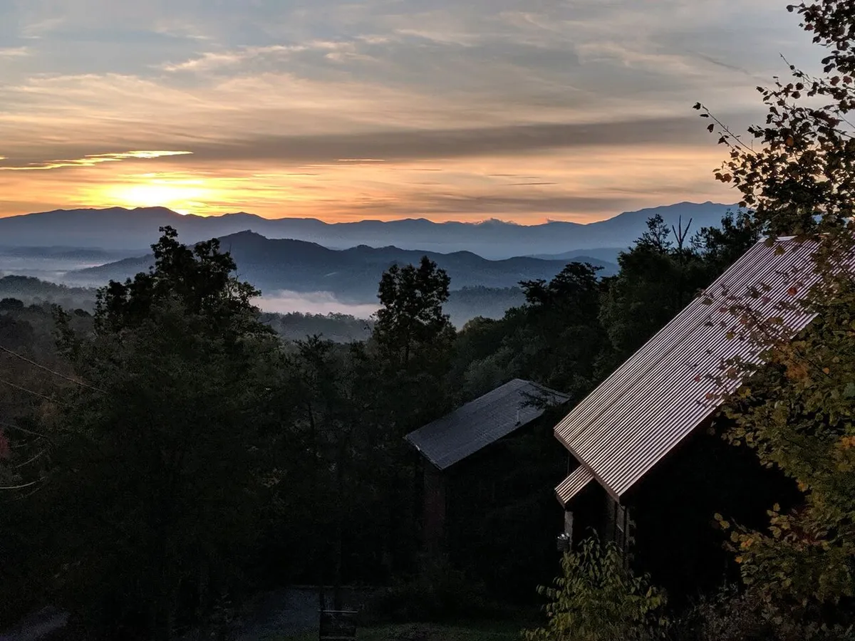 A sweeping view of the Smoky Mountains at sunset, with cabins nestled among trees. The tranquil landscape hints at opportunities for hiking, nature walks, and peaceful moments, aligning with the adventurous, dog-friendly activities described in the section.