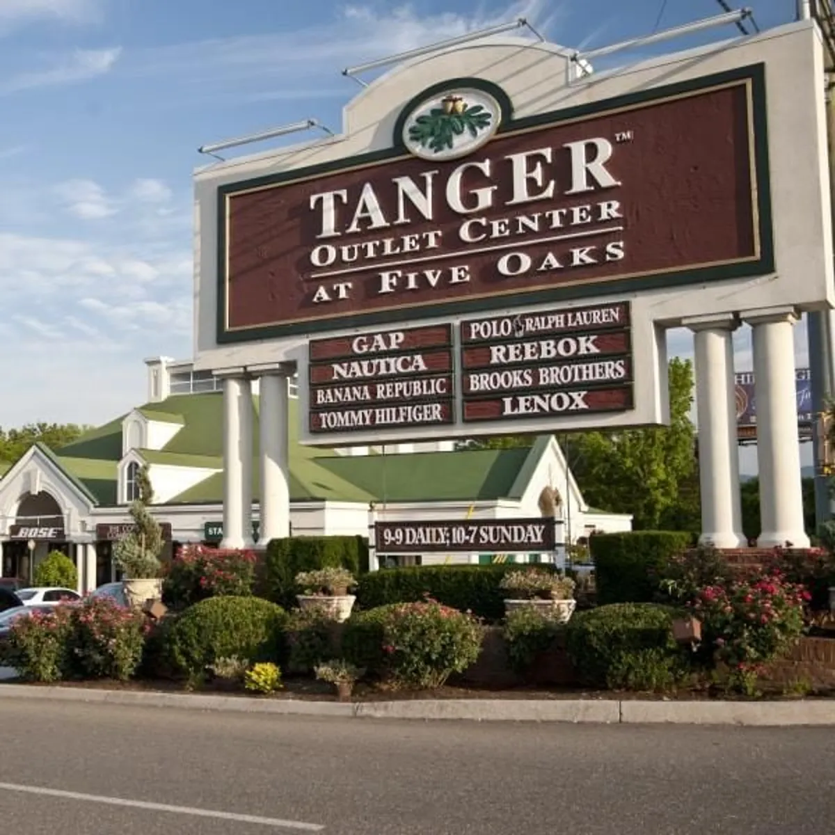The Tanger Outlet Center sign stands out amidst surrounding greenery and storefronts, suggesting nearby opportunities for shopping, dining, and socializing. The lively outdoor setting hints at the vibrant local attractions just a short drive from the cabin.