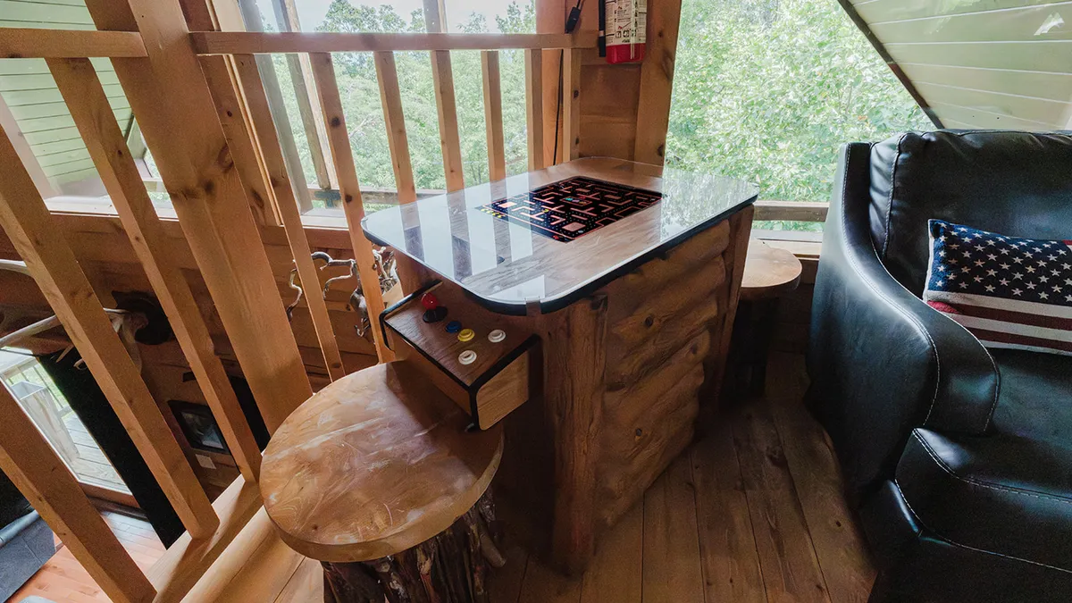 This image captures a unique game table in a cozy, wood-accented nook with comfortable seating, evoking a playful, relaxed mood. The setting is ideal for family game nights or friendly challenges among guests, as highlighted in the section.