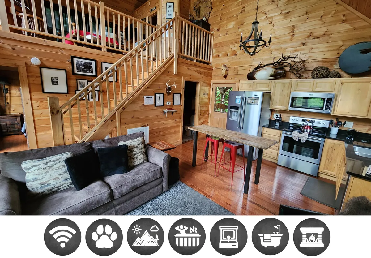 The image showcases the inviting interior of a cozy Smoky Mountains cabin, featuring a comfortable sofa near a rustic staircase, a spacious kitchen area, and a welcoming dining table—ideal for family gatherings, shared meals, and relaxing by the fireplace.